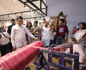 Goa Chief Minister Dr. Pramod Sawant closely examining a traditional handloom setup and red woven threads during the inauguration of the 'Weaves of Goan Natives' initiative.