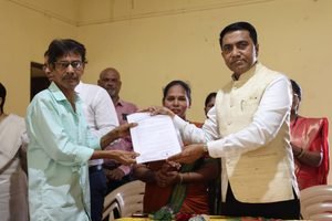 Goa Chief Minister Dr. Pramod Sawant handing over official compensation documents to an affected local beneficiary alongside government officials.